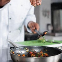 chef adding herbs to pan of food 400x300 1
