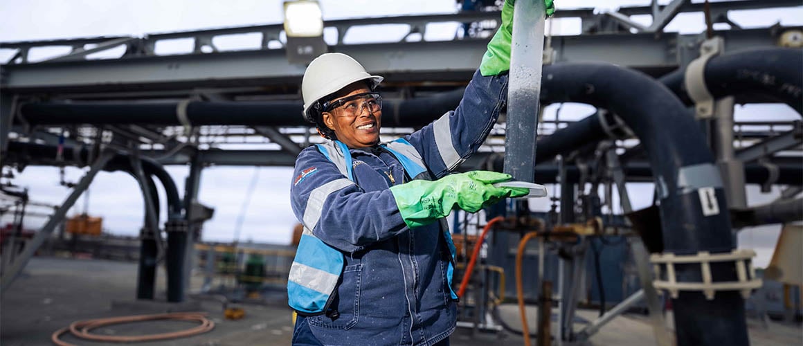 A mine worker in PPE holding a tube up in the air.